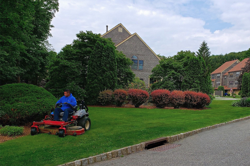 Worker mowing the lawn as part of the regular commercial property maintenance