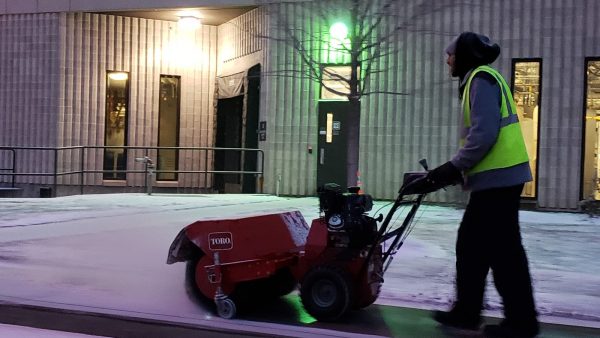 Worker removing melted snow from parking lots and icy sidewalk.