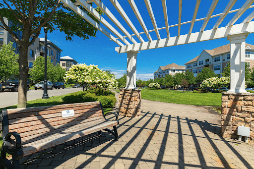 View of park bench and houses during early spring shows the beautiful lawn service done.