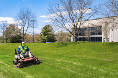 Maintenance worker on lawn with riding lawn mower